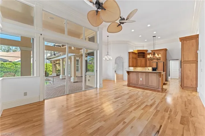 Unfurnished living room with crown molding, ceiling fan with notable chandelier, and light wood-type flooring