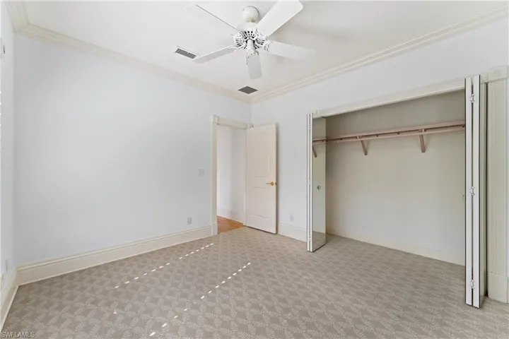 Unfurnished bedroom featuring light carpet, a closet, ceiling fan, and ornamental molding