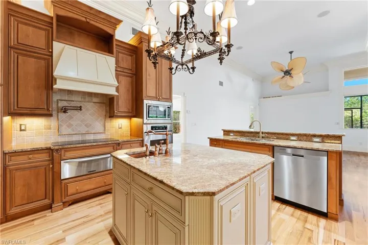 Kitchen featuring sink, premium range hood, an island with sink, pendant lighting, and appliances with stainless steel finishes