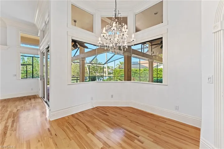 Unfurnished room featuring hardwood / wood-style flooring, crown molding, and an inviting chandelier