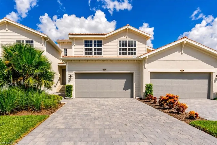 Elegant two-story residence featuring a concrete paver driveway, three-car garage configuration, and modern architectural design with peaked rooflines