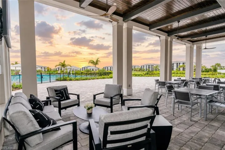 Expansive covered patio with exposed beam wood-finish ceiling, ceiling fans, column supports, and paver flooring