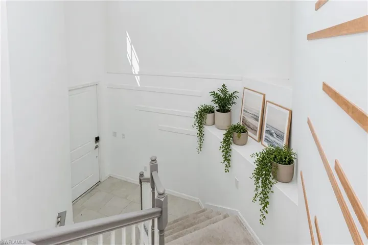 Staircase with carpeted treads and painted banister, featuring a white paneled wall accent