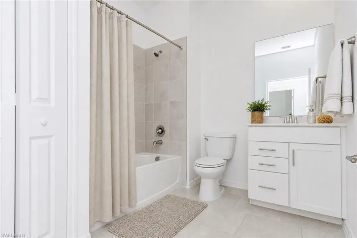 White vanity with brushed nickel hardware, integrated sink, and wall-mounted mirror