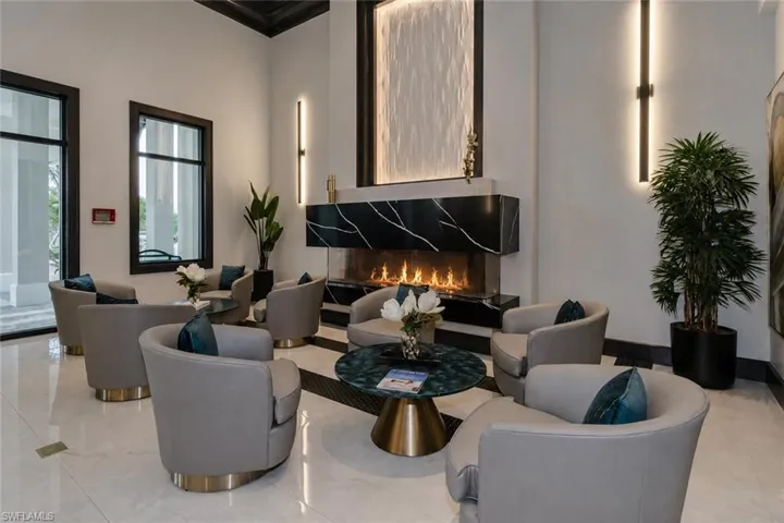 Recessed linear fireplace with a black and white veined marble surround, white tile flooring, and integrated wall sconces