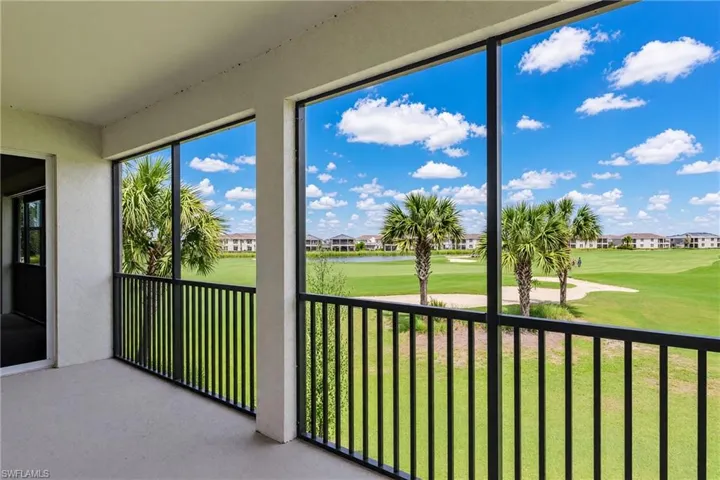 Screened balcony with concrete flooring, black metal railings, and an expansive golf course backdrop featuring mature palm trees and a pond