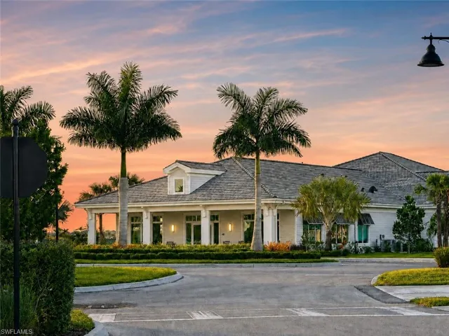 White exterior with a gray shingle roof, featuring a covered porch with white columns, dormer windows, and established landscaping