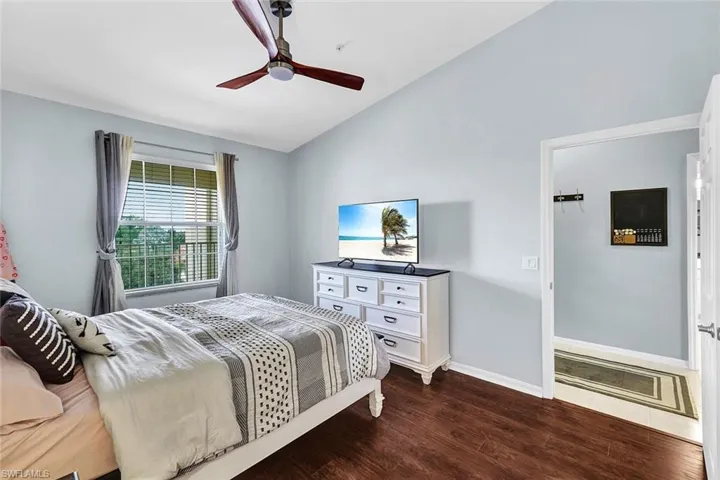 Bedroom with hardwood / wood-style floors, ceiling fan, and vaulted ceiling