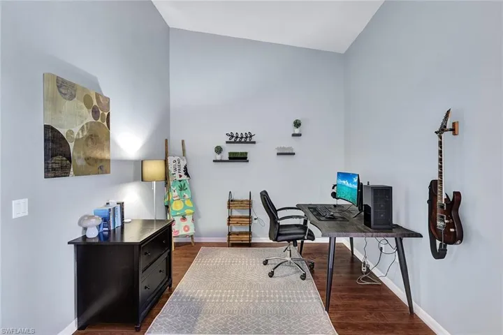 Office space featuring dark wood-type flooring and lofted ceiling