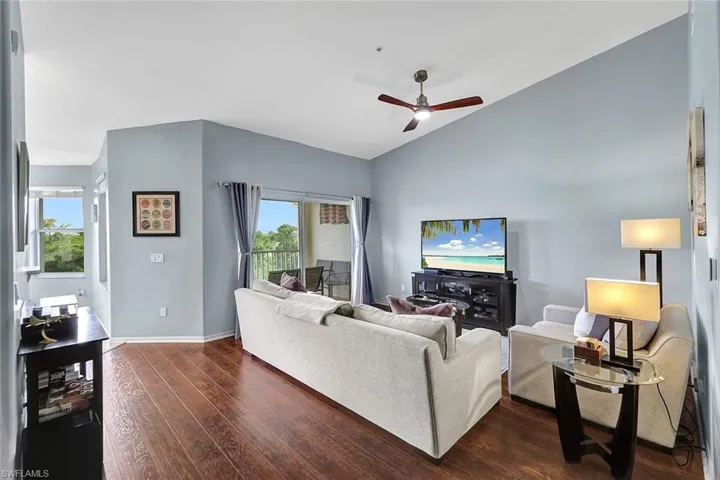 Living room featuring dark hardwood / wood-style floors, ceiling fan, and vaulted ceiling