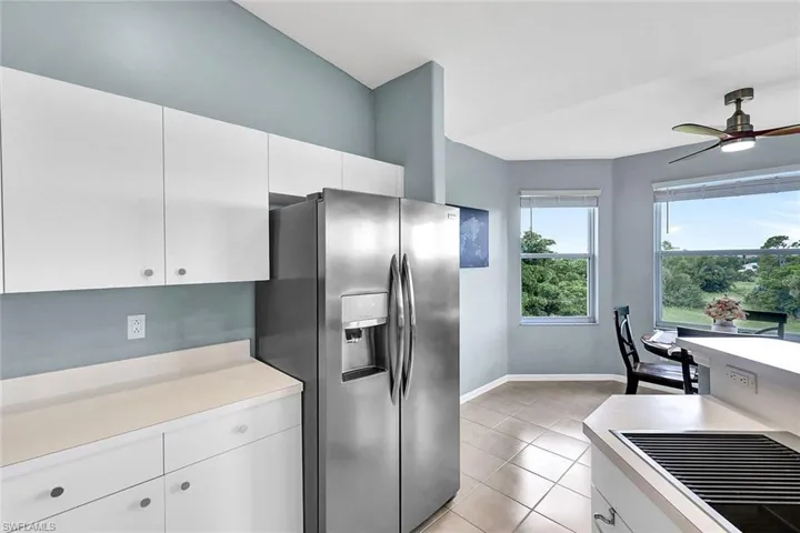 Kitchen featuring white cabinets, light tile patterned floors, stainless steel refrigerator with ice dispenser, and ceiling fan