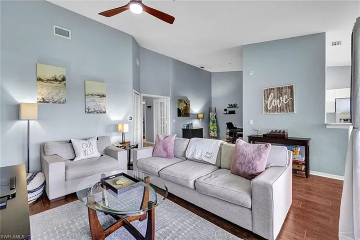 Living room with dark hardwood / wood-style floors, a towering ceiling, and ceiling fan