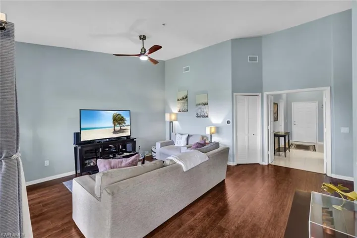 Tiled living room with ceiling fan and high vaulted ceiling