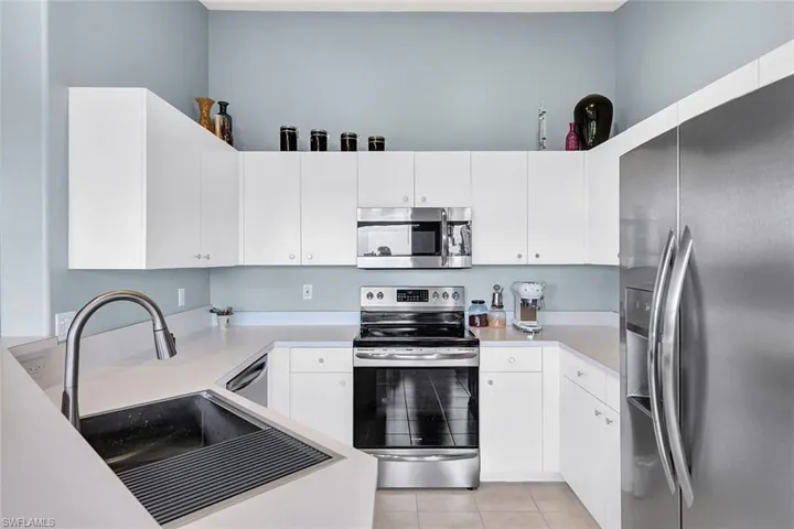 Kitchen featuring light tile patterned flooring, white cabinets, and stainless steel appliances