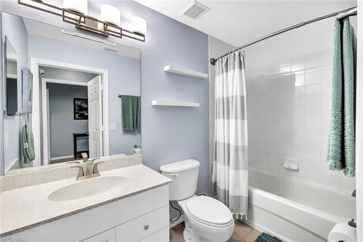 Full bathroom featuring tile patterned flooring, shower / bath combo with shower curtain, toilet, and vanity