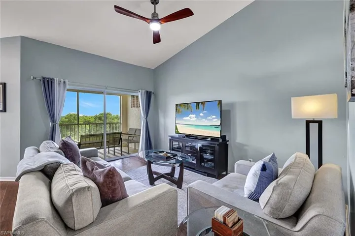 Living room featuring wood-type flooring, high vaulted ceiling, and ceiling fan