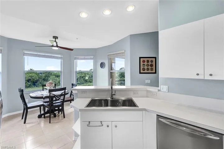Kitchen featuring sink, kitchen peninsula, light tile patterned floors, dishwasher, and ceiling fan
