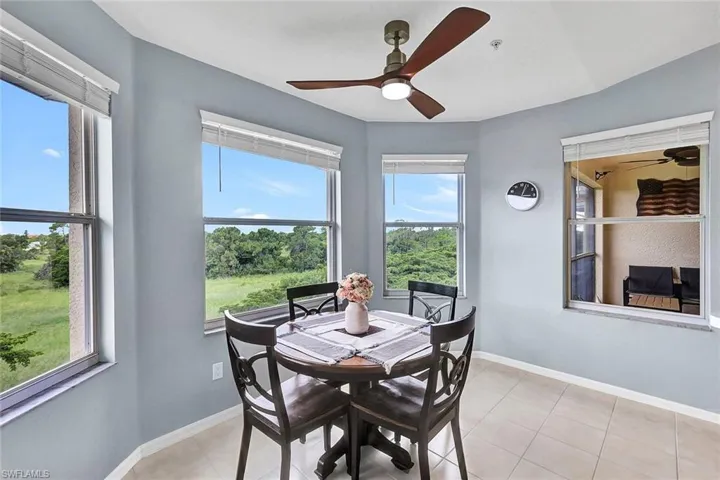 Dining area with light tile patterned flooring, a wealth of natural light, and ceiling fan