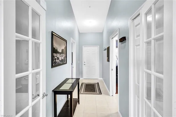 Hall with light tile patterned flooring and french doors