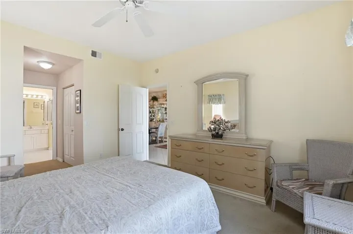 Bedroom with light colored carpet, a ceiling fan, connected bathroom, and a closet