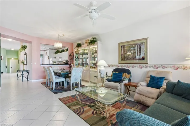 Living room featuring light tile patterned floors, ceiling fan, and a chandelier