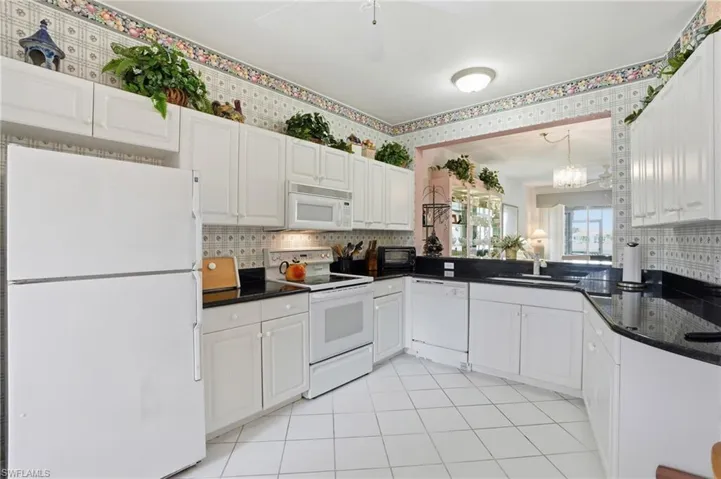 Kitchen with white appliances, white cabinets, and decorative backsplash
