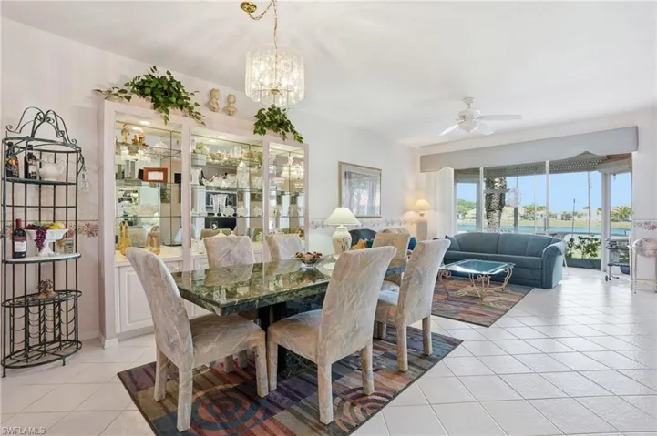 Dining room with ceiling fan, light tile patterned floors, and a chandelier