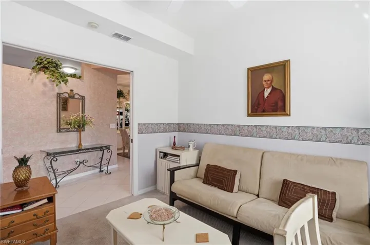 Tiled living room featuring ceiling fan and carpet