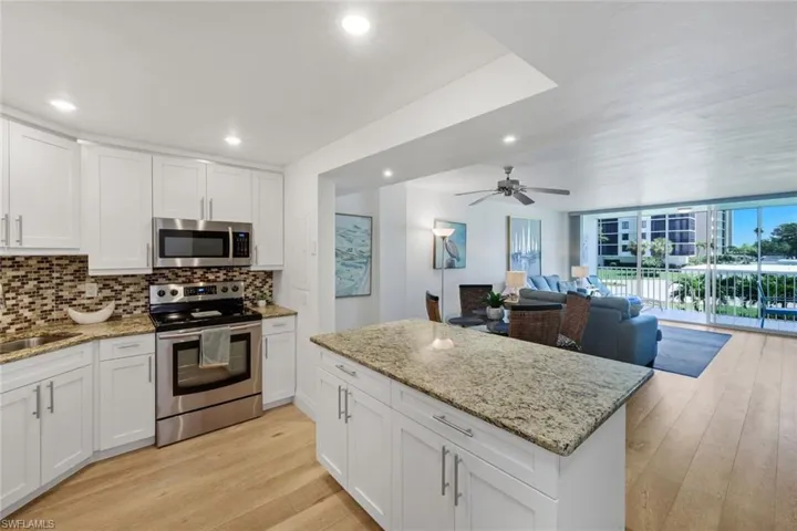 Kitchen featuring white shaker cabinetry, stainless steel appliances, a tile backsplash, and granite countertops