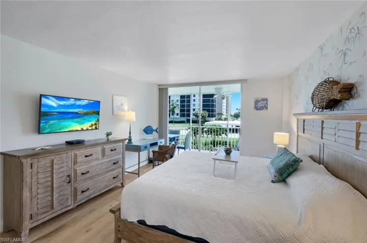 Bedroom includes a wall-mounted television, king size bed, dresser and desk.