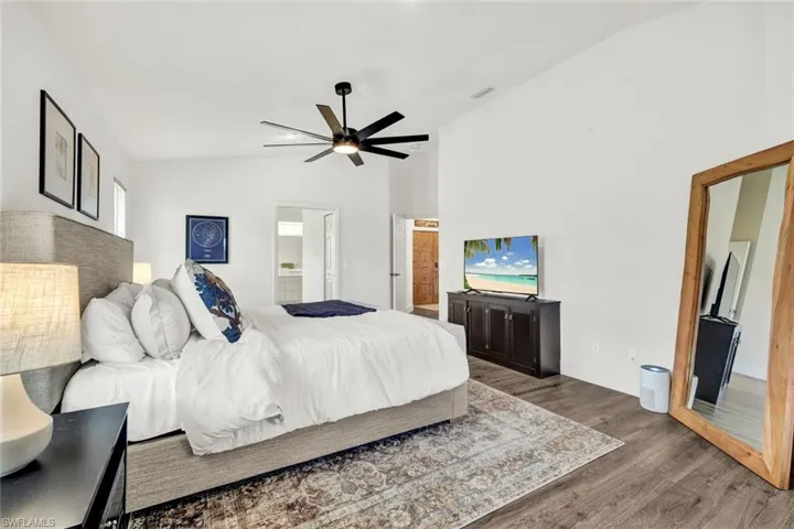 Bedroom 1  featuring ensuite bath, lofted ceiling, ceiling fan, and wood finished floors