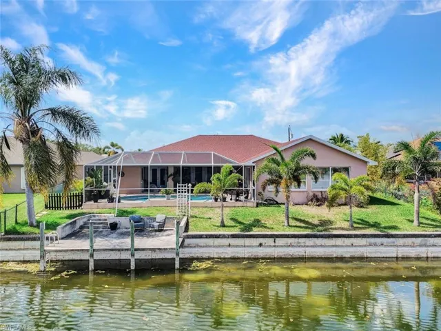 Back of house featuring a water view, a sunroom, an outdoor pool, a lanai, and stucco siding
