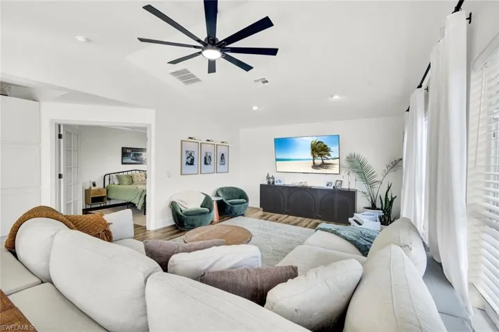 Living room with lofted ceiling, wood finished floors, a ceiling fan, and recessed lighting