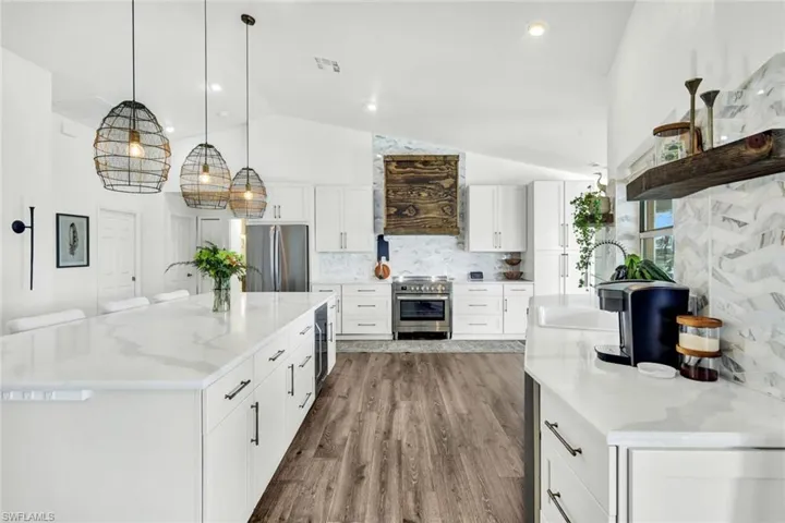 Kitchen with white cabinets, tasteful backsplash, stainless steel appliances, a spacious island, and dark wood-style flooring
