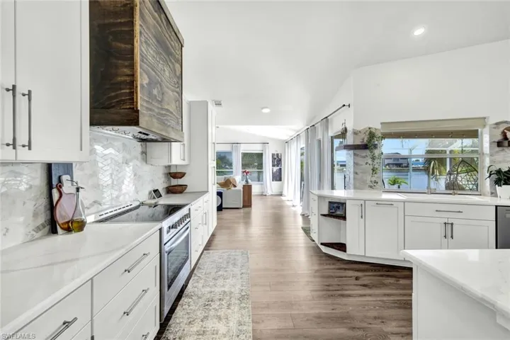 Kitchen with open shelves, stainless steel appliances, white cabinetry, backsplash, and recessed lighting