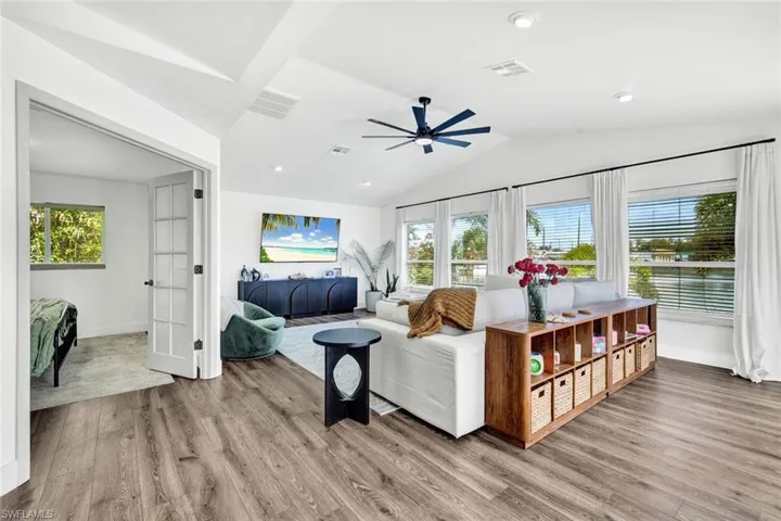 Living room featuring light wood-type flooring, lofted ceiling, a ceiling fan, and french doors