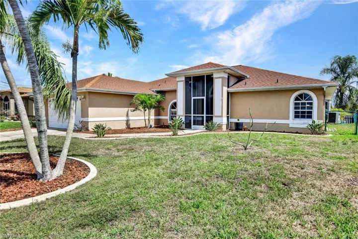 View of front of home with stucco siding, a sunroom, and a front yard