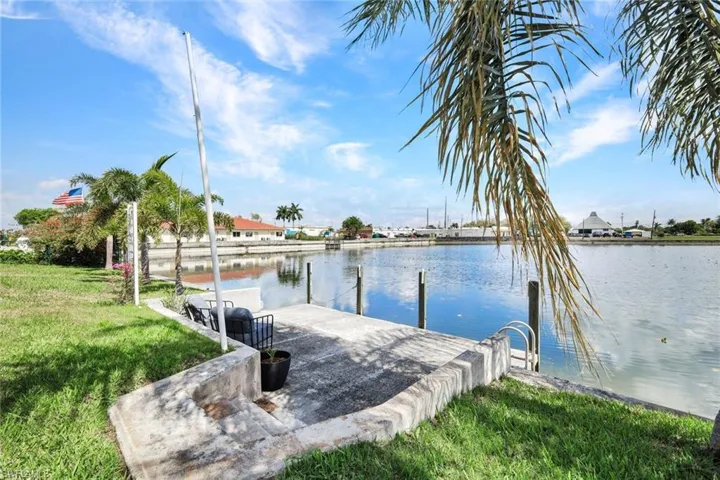 Dock area featuring a water view, a lawn, and a patio