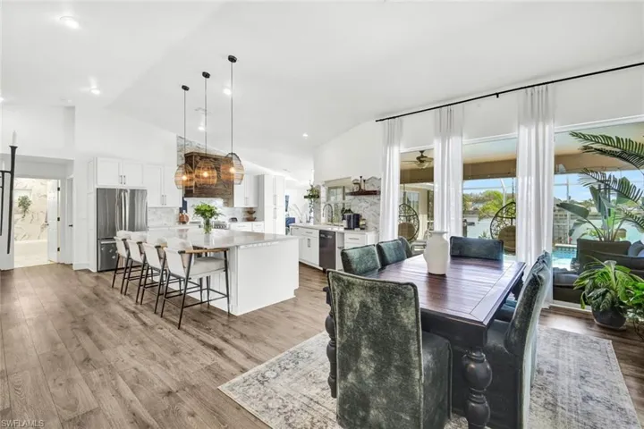 Dining room with lofted ceiling, light wood-style floors, and a ceiling fan