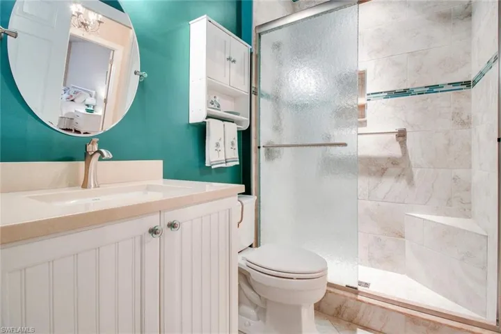 Bathroom with a shower with shower door, vanity, toilet, and tile patterned flooring