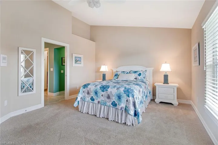 Bedroom featuring ceiling fan, light carpet, and high vaulted ceiling