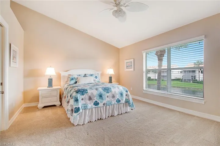 Bedroom with ceiling fan, lofted ceiling, and light colored carpet