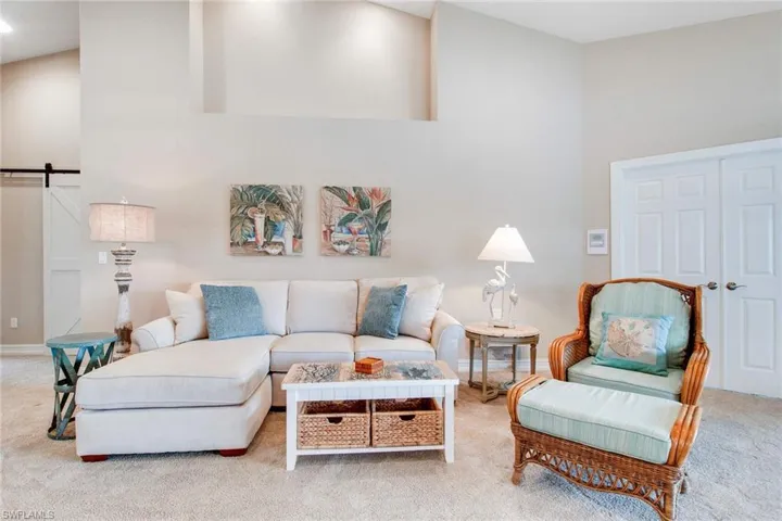 Living room featuring a barn door, a towering ceiling, and light carpet