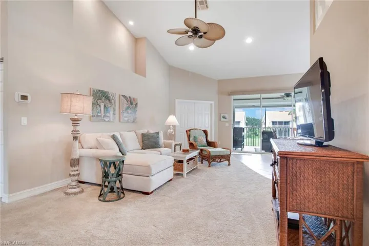 Living room with high vaulted ceiling, light carpet, and ceiling fan