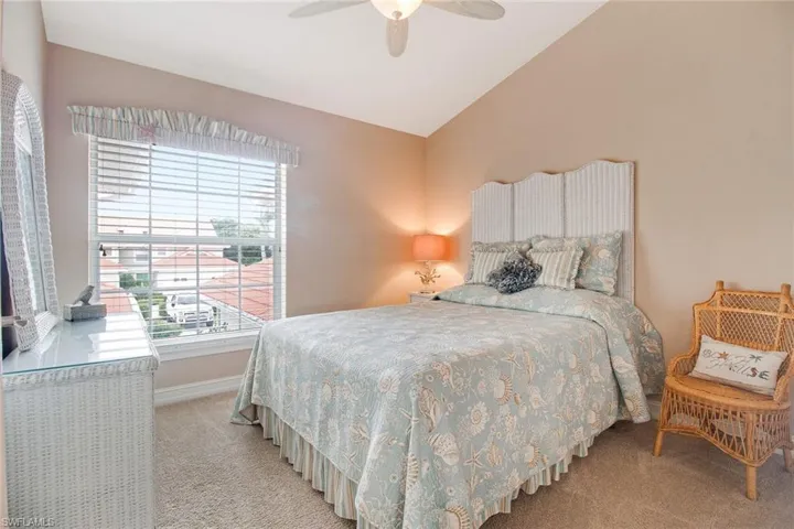Carpeted bedroom featuring ceiling fan and vaulted ceiling