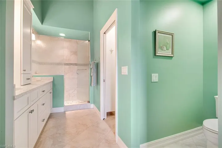 Bathroom with tiled shower, toilet, and vanity