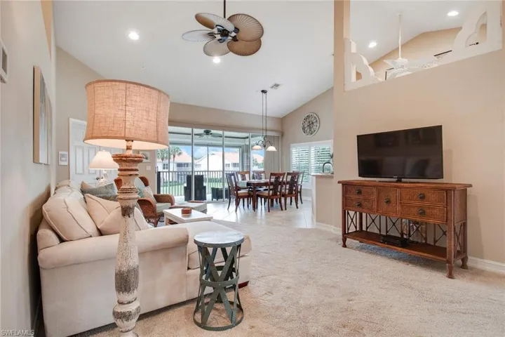 Carpeted living room featuring high vaulted ceiling and ceiling fan