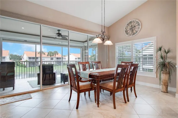 Dining area with ceiling fan with notable chandelier, lofted ceiling, and light tile patterned floors