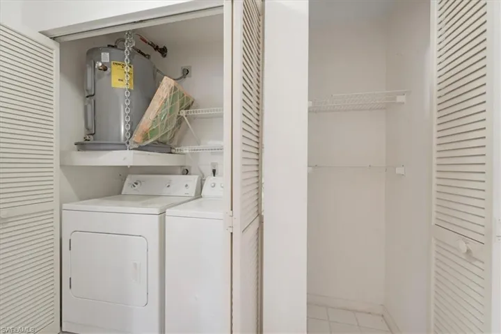 Washroom featuring electric water heater, electric dryer hookup, independent washer and dryer, and light tile floors