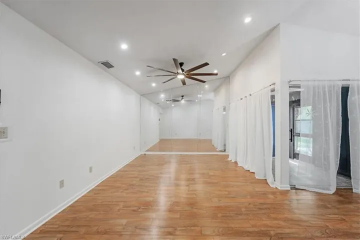 Spare room with light hardwood / wood-style floors, ceiling fan, and vaulted ceiling